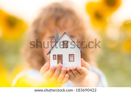 House in hand against spring green background. Real estate concept
