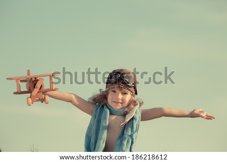 Happy kid playing with toy airplane against summer sky background