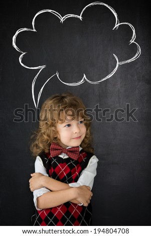 Smart kid in class. Happy child against blackboard. Drawing speech bubble cloud. Copy space for your text