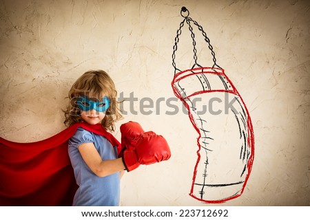 Superhero kid in red boxing gloves. Child punching on the drawn bag. Winner and success concept