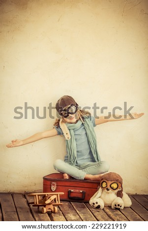 Happy child with retro toys. Funny kid dressed in pilot playing at home. Retro toned image