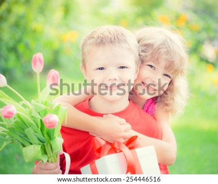 Happy children with bouquet of flowers. Boy and girl against green background. Spring family holiday concept. Women\'s day