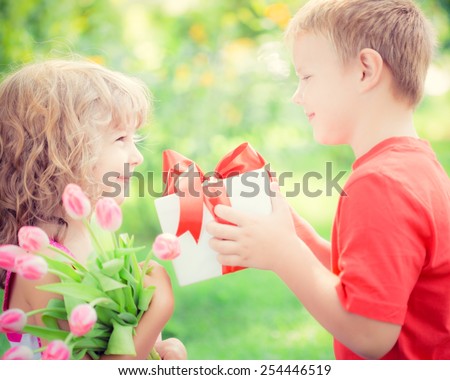 Happy children with bouquet of flowers. Boy and girl against green background. Spring family holiday concept. Women\'s day