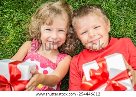 Happy children with bouquet of flowers. Boy and girl against green background. Spring family holiday concept. Women\'s day. Unusual top view portrait