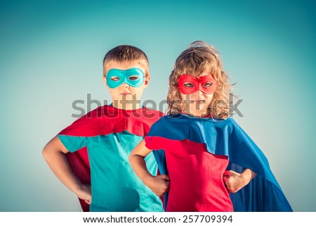Superhero children against summer sky background. Kids having fun outdoors. Boy and girl playing. Success and winner concept