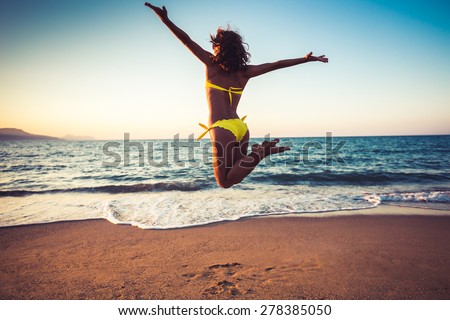 Happy young woman jumping on the beach. Summer vacation and freedom concept