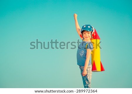 Happy child playing with toy rocket against summer sky background