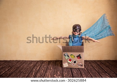Happy child playing in cardboard box. Kid having fun at home