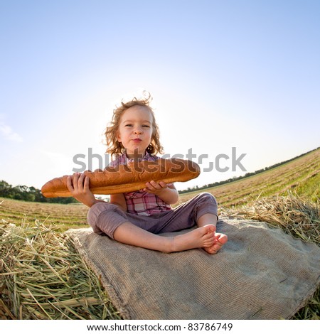 Child eating bread in autumn field. Shot was taken with fisheye lens; sunny back lighting