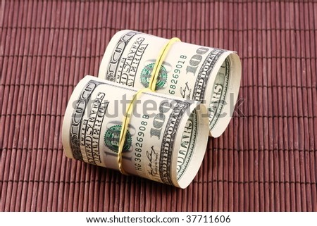 US paper currency bills rolled up and tied with a yellow rubber band