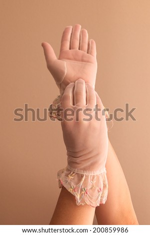 Image of woman\'s forearms and hands modeling vintage lace see through gloves.