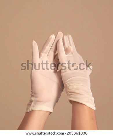 A woman\'s hands and forearms are shown as she models a vintage pair of formal white gloves . She seems to be adjusting the finger length