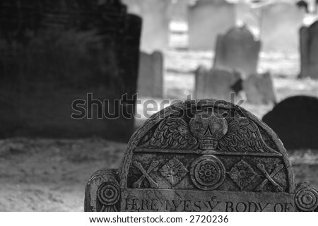 ornate ancient grave stone detail showing winged skull with cross bones and flowers