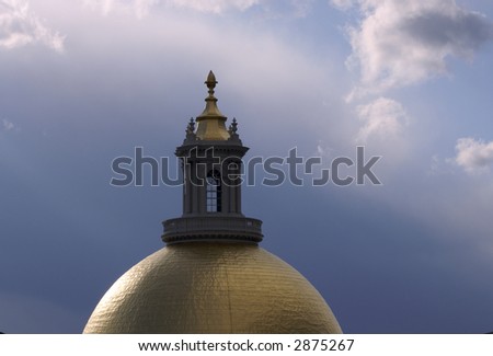 the massachusetts state house dome, covered in gold,  lit by the afternoon sun with two types of clouds adding a painterly, almost surreal look to the image
