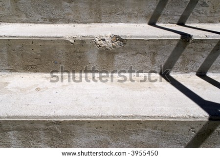simple image of broken cement stairs with shadow of railing