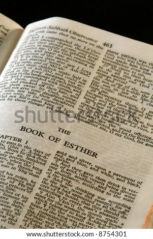 bible series, detail of an old antique holy bible against a black background open to the book of esther old testament