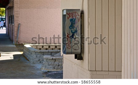 graffiti covered public pay telephone on outside wall