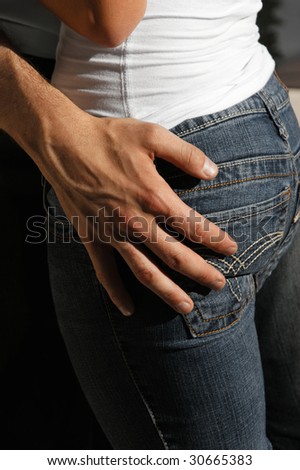 man resting his hand on woman\'s hip she is wearing tight jeans outdoors in the hot afternoon sunshine