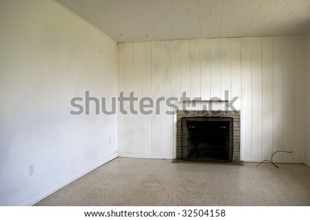 An old abandoned house interior with paneled wall and fireplace in need of repair.