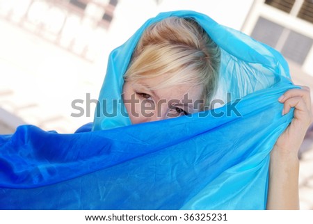 beautiful fair haired skinned woman with blonde hair and brown eyes peeking out from blue silk