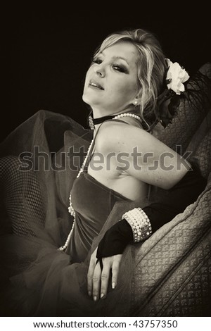 A pretty blonde woman is laying back on her elbows with head tilted back looking at viewer in sexy outfit in sepia