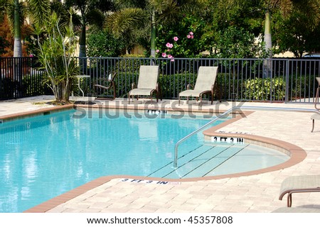 an outdoor swimming pool in florida with chairs.