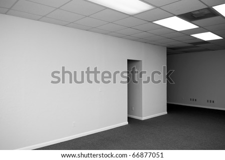 a large empty room with an opening and a drop ceiling in a vacant office building