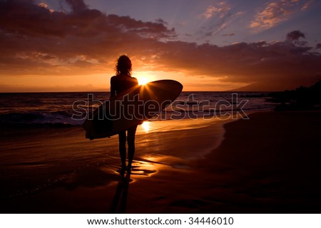 silhouette woman on tropical beach holding surfboard at sunset in maui