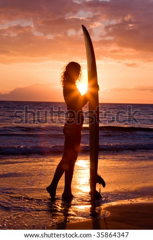 beautiful woman with surfboard standing at tropical sunset