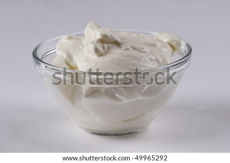 Sour cream in the glass sauce bowl isolated over grey background