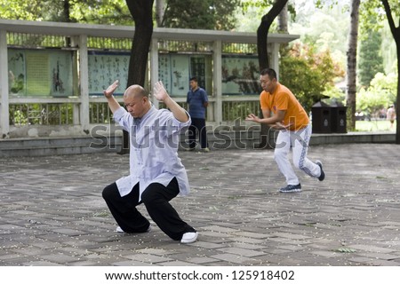 BEIJING, CHINA - JULY 7: Chinese master of martial arts teaching Tai Chi in a park in Beijing on July 7, 2012. Tai Chi is popular in China for both its defense training and health benefits.