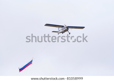 TVER, RUSSIA - JULY 09: Yak-12 plane tows Russian flag during the Tver Blue Skies aviation festival on July 09, 2011 in Tver, Russia