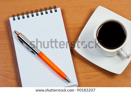 Notebook with pen and coffee on table top view.
