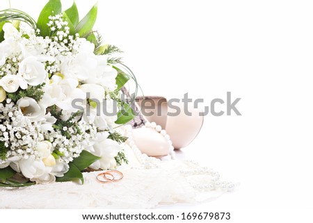 Wedding rings on lace against wedding bouquet and shoes