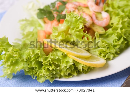 Fresh salad with shrimps and avocado. Focus on foreground(lemon)