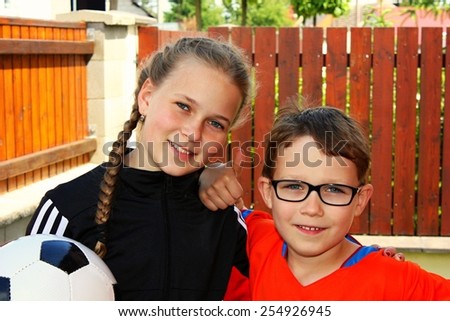 Portrait of two little children with a ball looking at camera and smiling, brother and sister