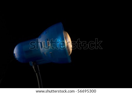 The desktop dark blue lamp burns on a black background, focus on a lamp