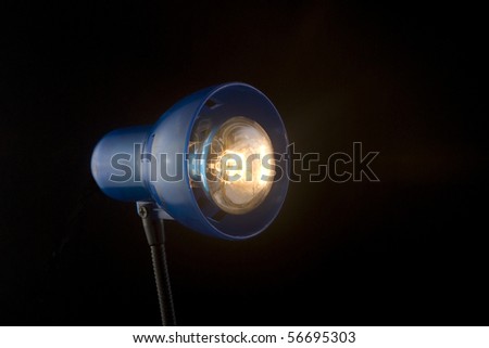 The desktop dark blue lamp burns on a black background, focus on a lamp