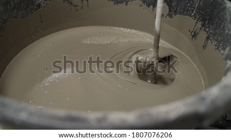 The liquid flooring compound is mixed in a bucket. The mortar is mixed in a bucket. fresh wet mixed cement mortar with trowel inside bucket by close up view Foto stock © 