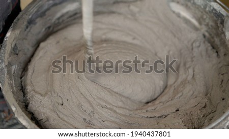 The worker mixes the mortar. Wet Concrete or motrar mixing texture. Gray mortar, concrete surface. The solution is stirred, apartment renovation. ストックフォト © 