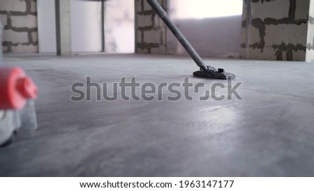 Close-up - cleaning with a construction vacuum cleaner. Removal of dust and dirt. A worker vacuums a concrete floor. Worker washes the floor with a vacuum cleaner. Worker with an industrial vacuum