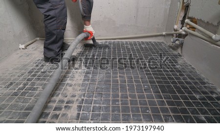 A worker is cleaning dust with a vacuum cleaner on the floor. Cleaning service. dust removal with vacuum cleaner. Worker removes dust with a vacuum cleaner. Worker vacuuming the floor before