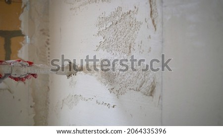 Machine application of mortar to the wall. Machine application of plaster to the wall. Plasterer throws plaster on the wall. Plastering walls in a new house. Stockfoto © 