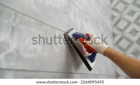 Seam grouting with black grout. Tile grout. Construction work with ceramic tiles. Grouting, joining wall tiles. The builder processes the seams between ceramic tiles. Foto stock © 
