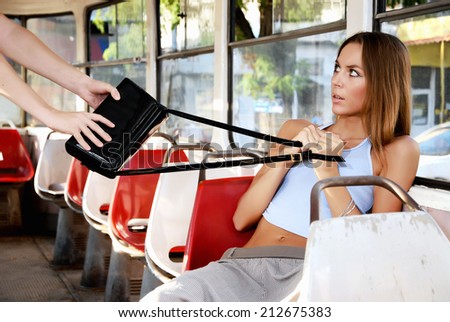 Frightened woman and a thief. Robber stealing a woman\'s handbag in a train.