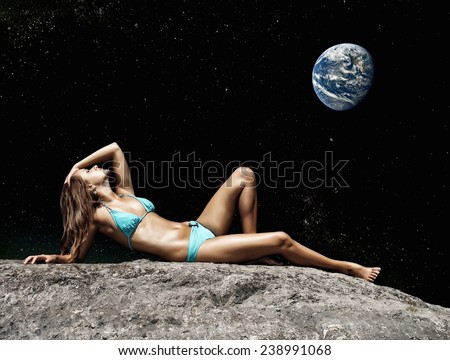 Holidays on the Moon. Woman lying on the ground in the night sky with the Earth. Elements of this image furnished by NASA.