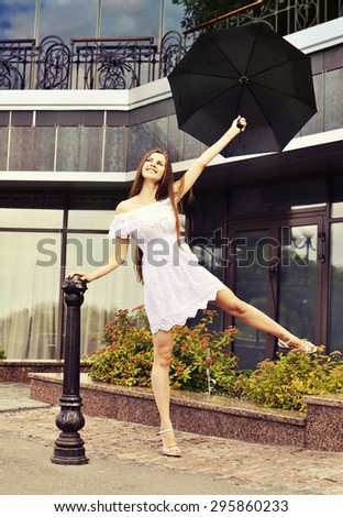 After the rain. Happy girl in a white dress with umbrella on the street
