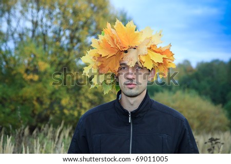The young man with a wreath on a head, twisted from yellow leaves of a maple.