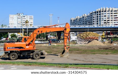 OMSK, RUSSIA - AUGUST 11, 2011: OMSK, RUSSIA - AUGUST 11, 2011: Construction site of first metro station \'Pushkin Library\'  with excavator closeup, mounting underpass,  metro bridge on back plane