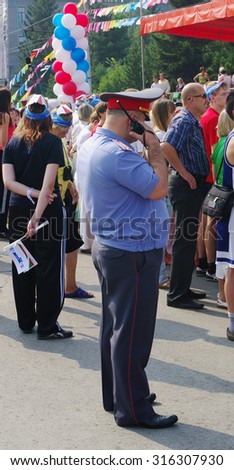 OMSK, RUSSIA  - AUGUST 07, 2010: Police officer closeup says on portable radio in hand on duty at public event